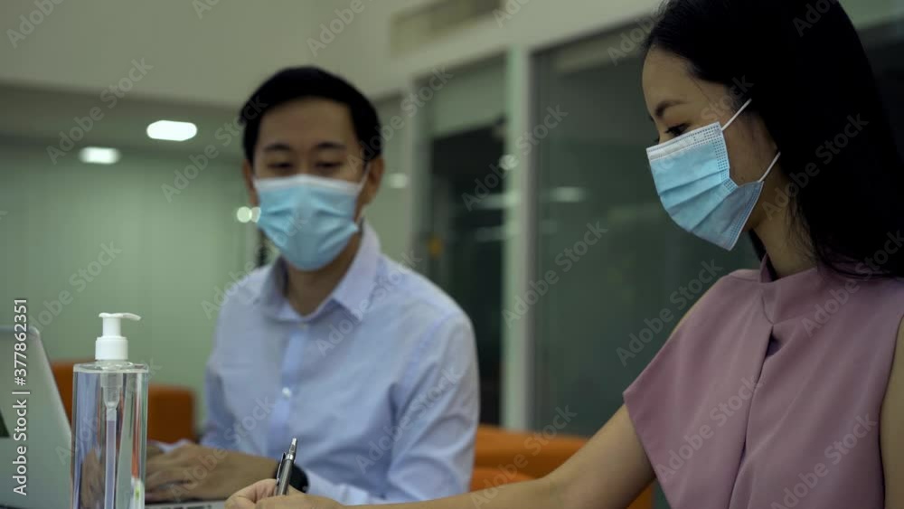 Two business coworkers sitting at table wearing protective Covid-19 face mask coverings, new normal, protection, health, safety - 4K High Quality Footage