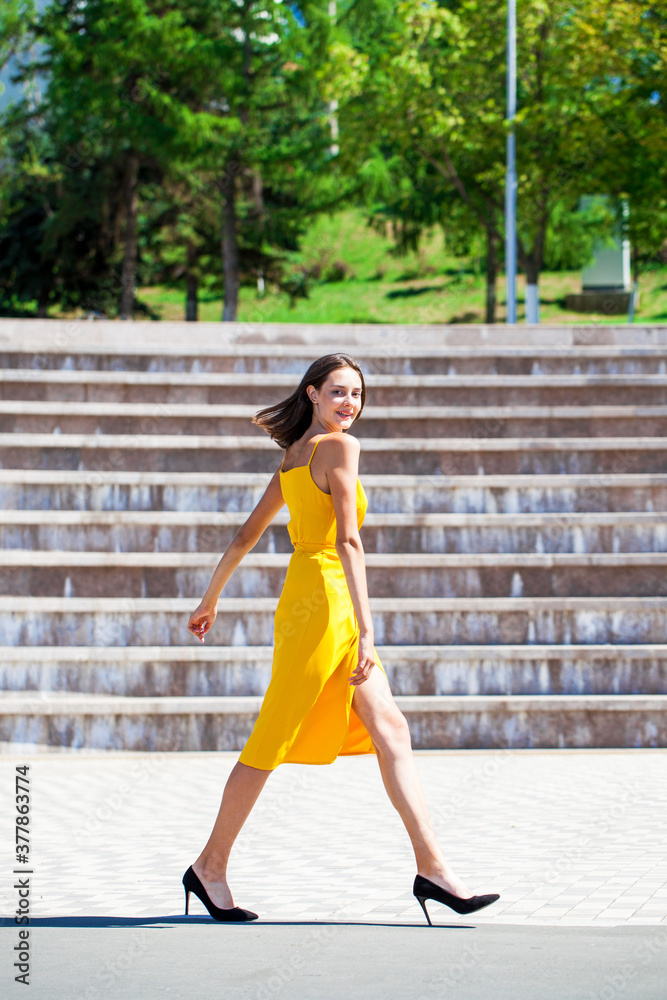 Obraz premium Young beautiful brunette woman in yellow dress