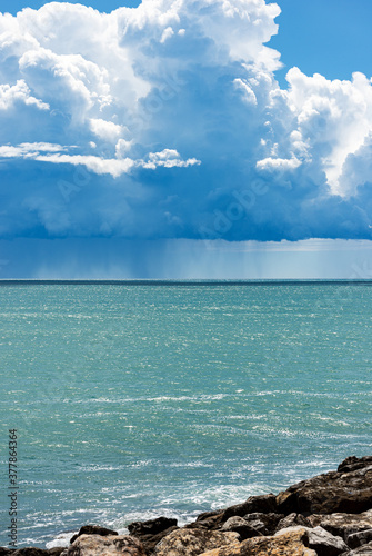 Cumulus Clouds and Torrential Rain on the Horizon over the Mediterranean Sea in front of the ancient village of Tellaro, Gulf of La Spezia, Liguria, Italy, Europe