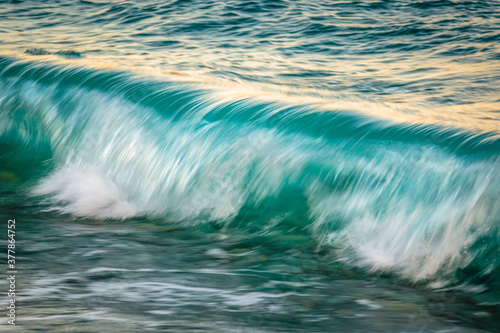 close-up of a turquoise blue wave crashing with motion blur.