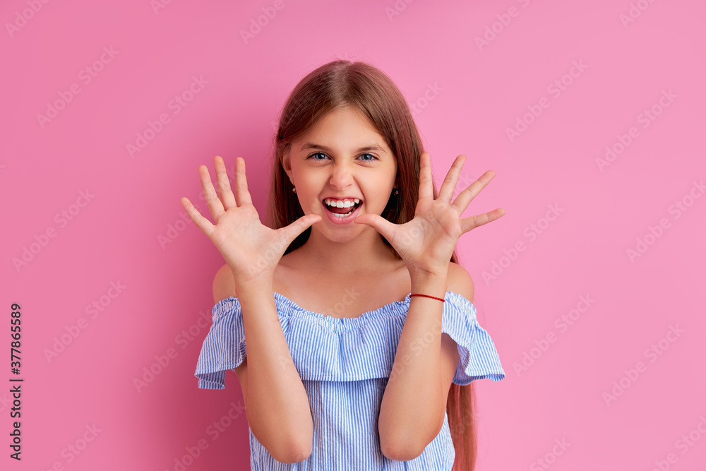 funny caucasian teen girl scaring someone at camera, frighten, show claws as cat, have fun. isolated pink background funny caucasian teen girl scaring someone at camera, frighten, show claws as cat, have fun. isolated pink background