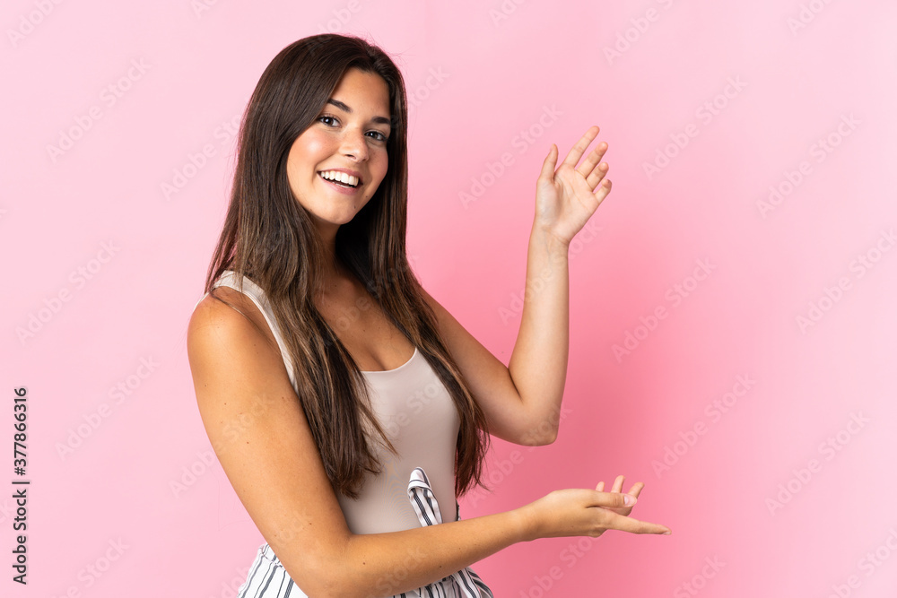 Young brazilian woman isolated on pink background extending hands to the side for inviting to come Young brazilian woman isolated on pink background extending hands to the side for inviting to come