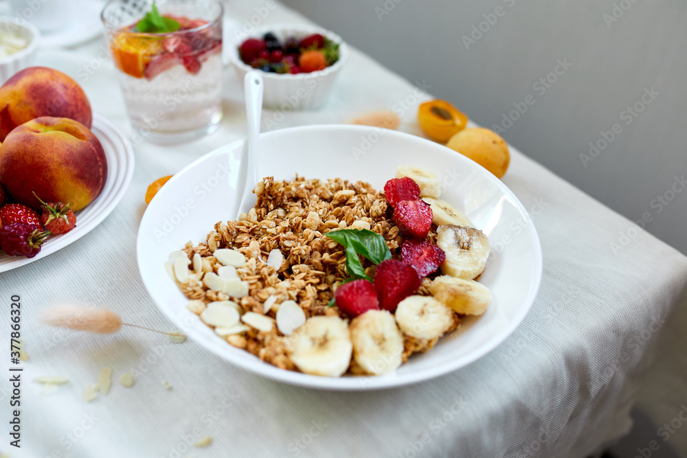 Healthy breakfast bowl, fresh granola, muesli with berries strawberry, banana on white table, Top view, Copy space. Clean eating, detox, dieting, vegetarian food concept