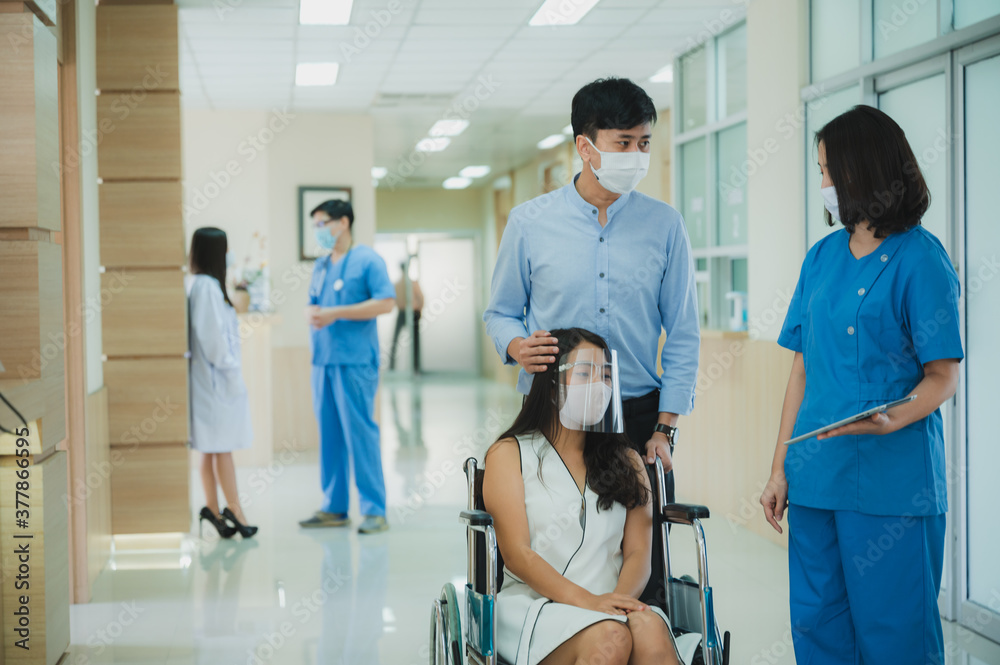 The smiling doctor and medical nurse staff take care of wheel chair patient at the healthcare hospital by wearing face mask and stethoscope