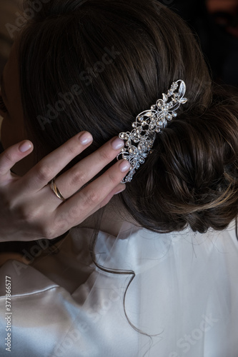 Back view of bride adjusting elegant hair clip with hand close up. Morning of the bride. Wedding day concept.