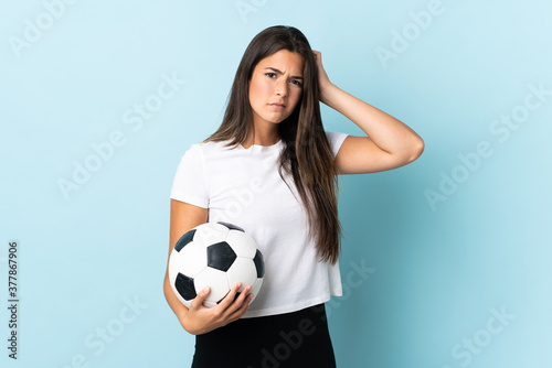Young football player brazilian girl isolated on blue background having doubts © luismolinero