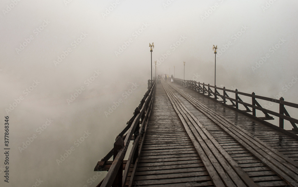 Mon wood bridge in the morning in the fog down (Sangkhla Buri, Kanchanaburi, Thailand) This Mon wood bridge is officially named Uthamanusorn Bridge. Focus and blur.