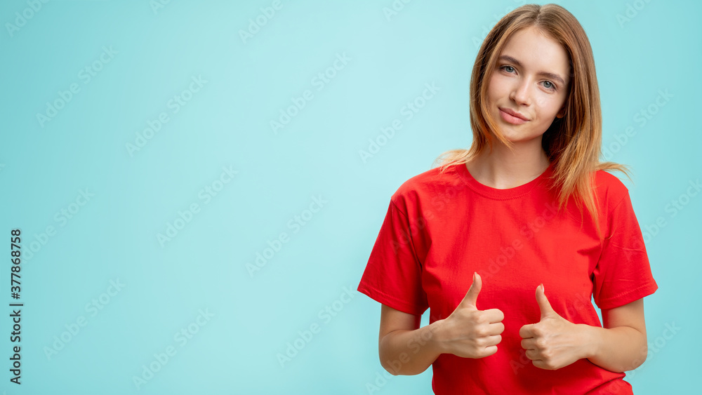 Like gesture. Special offer. Portrait of satisfied confident woman in red t-shirt approving choice with thumbs up smiling isolated on blue copy space advertising background. Agreement acceptance. Like gesture. Special offer. Portrait of satisfied confident woman in red t-shirt approving choice with thumbs up smiling isolated on blue copy space advertising background. Agreement acceptance.