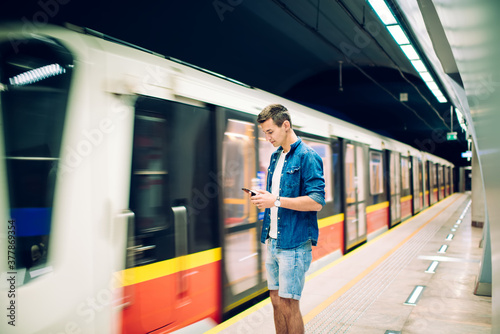 Serious man with smartphone standing near moving train