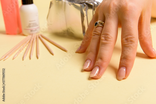 The procedure for removing varnish from nails hybrid nails in progress. Gel nail polish remover foils on woman's hands.