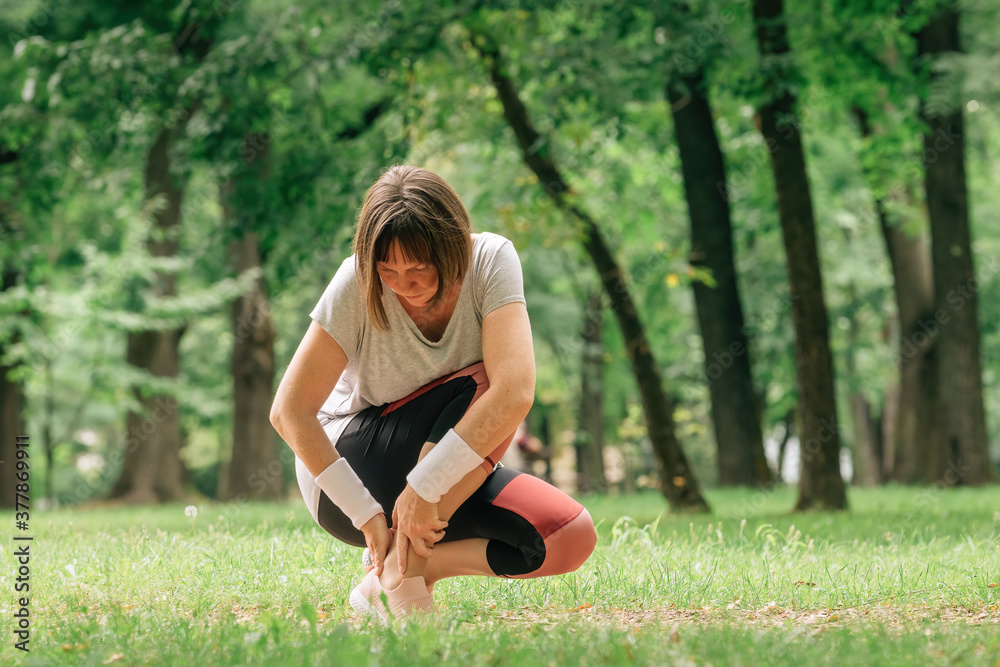 Female jogger with painful ankle injury during park jogging activity Female jogger with painful ankle injury during park jogging activity