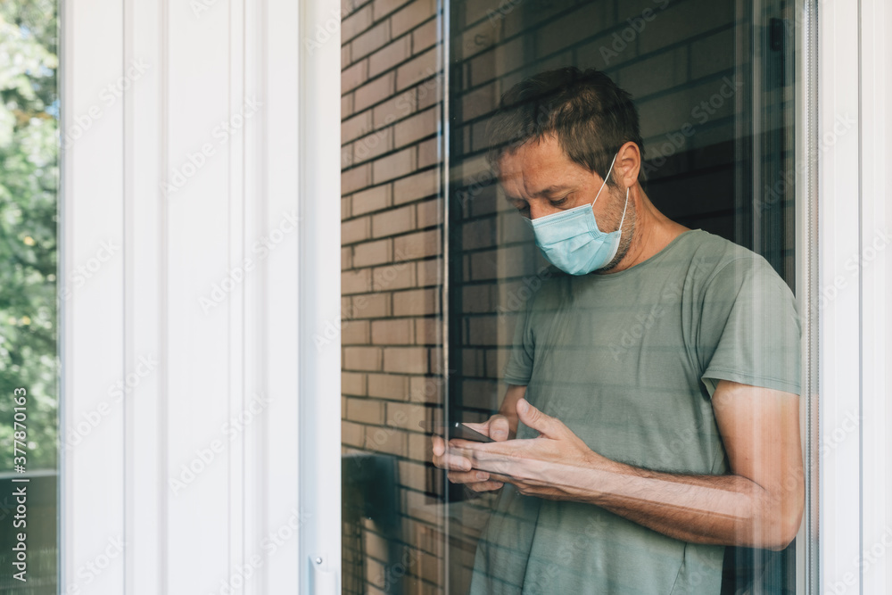 Man texting on mobile phone in self-isolation during coronavirus outbreak