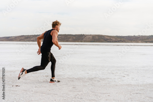 Image of caucasian athletic sportsman running while working out