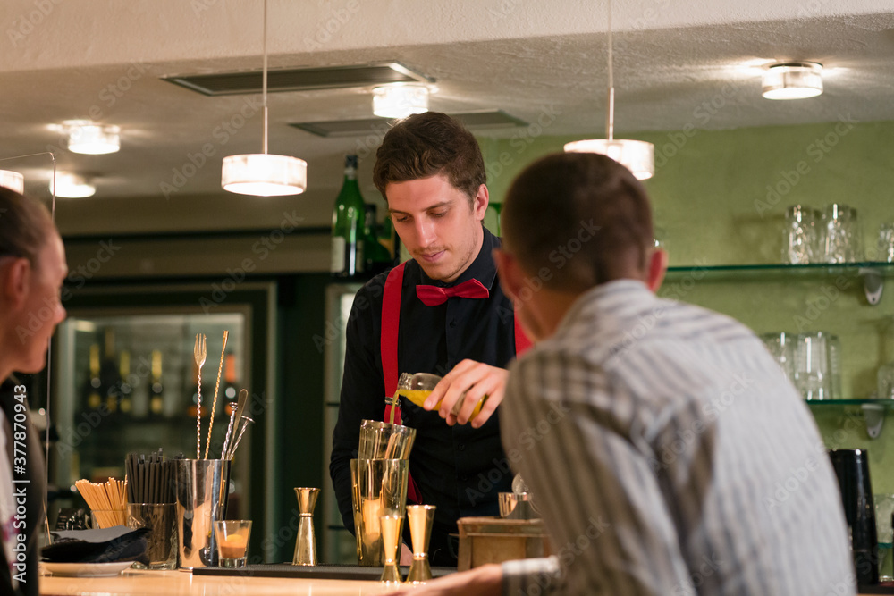 Male bartender preparing cocktail for clients