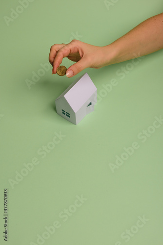 White family paper house in man hand on mint background paper. Minimalistic and simple concept, style. Copy space. Horizontal orientation.