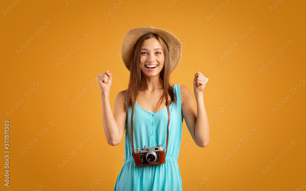 Emotional girl tourist with camera raising fists up
