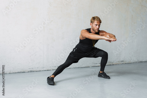 Attractive healthy uong sports man stretching indoors