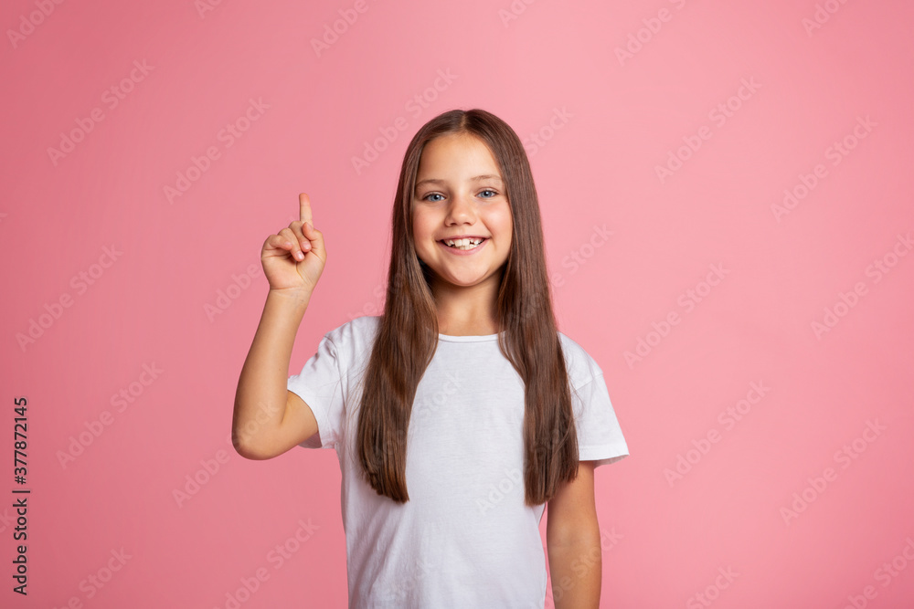 Little beauty casual style. Smiling girl points finger up Little beauty casual style. Smiling girl points finger up