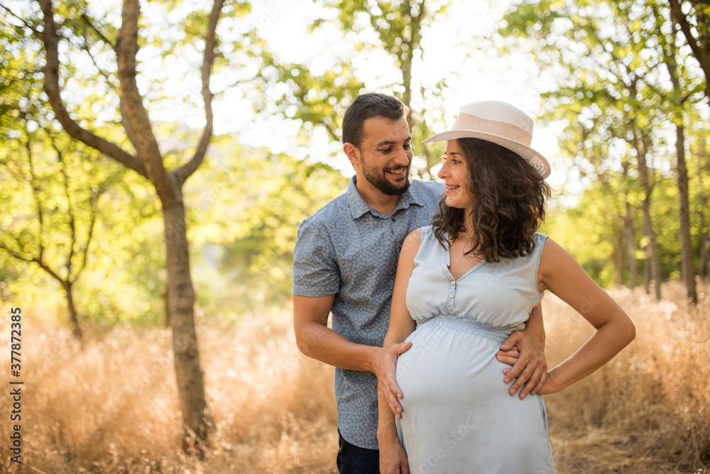 Couple waiting for a baby posing in the trees with sunset light. Couple waiting for a baby posing in the trees with sunset light.