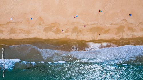 Drone image from above of an Andalusian beach in south Spain with waves breaking on the shore in summer