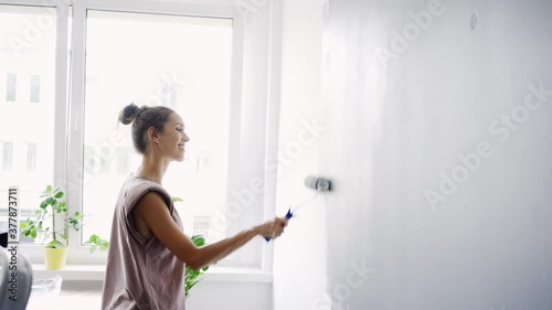 Young woman painting wall in apartment