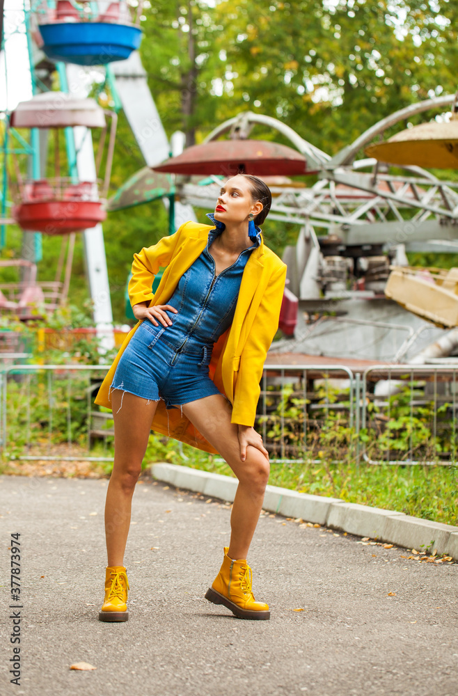 Young woman in yellow coat and denim overalls