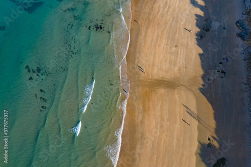 Aerial image of a sand beach in Cadiz with people taking a walk on the shore with clear blue water