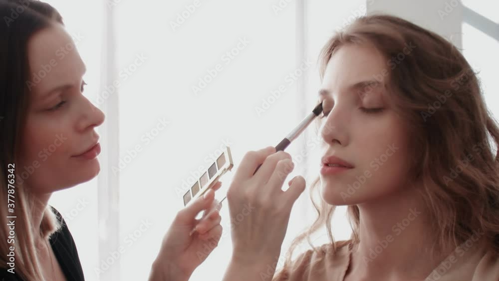 Professional stylist make-up artist makes eye makeup model. Face model with evening makeup close up view Professional stylist make-up artist makes eye makeup model. Face model with evening makeup close up view