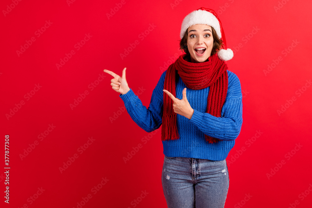 Surprised shocked girl in santa claus headwear cap point finger copyspace impressed season tradition discount wear blue knitted pullover denim jeans isolated bright shine color background