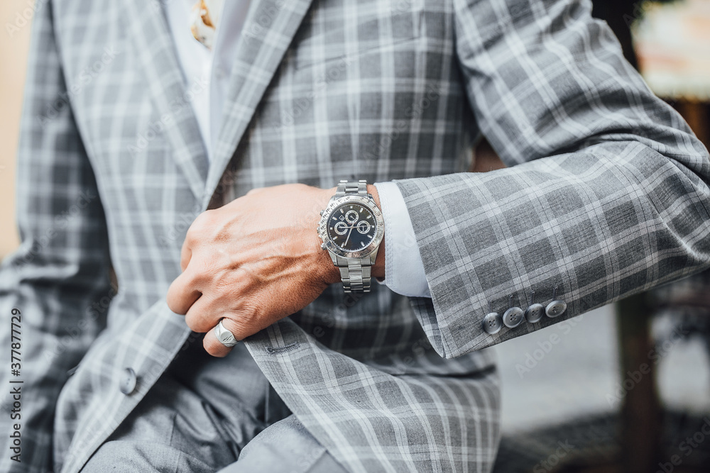 Concentration in a stylish gray suit, with a expensive clock