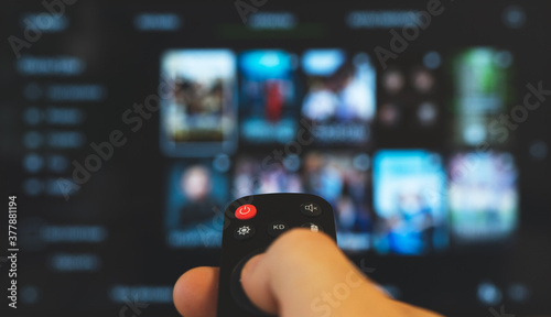 Male hand with remote control pointing on Smart TV.