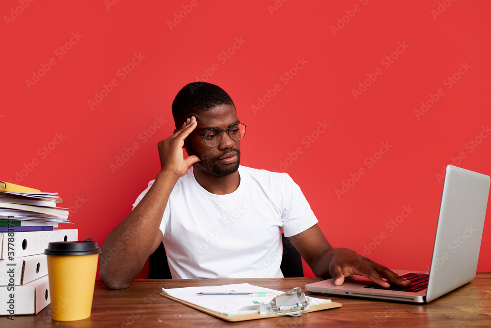 young sad and depressed african man working in stress at office computer  desk feeling overwhelmed, frustrated black guy is suffering headache and  depression isolated over red background Stock Photo | Adobe Stock