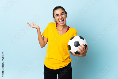 Young hispanic football player woman over isolated on blue background with shocked facial expression © luismolinero