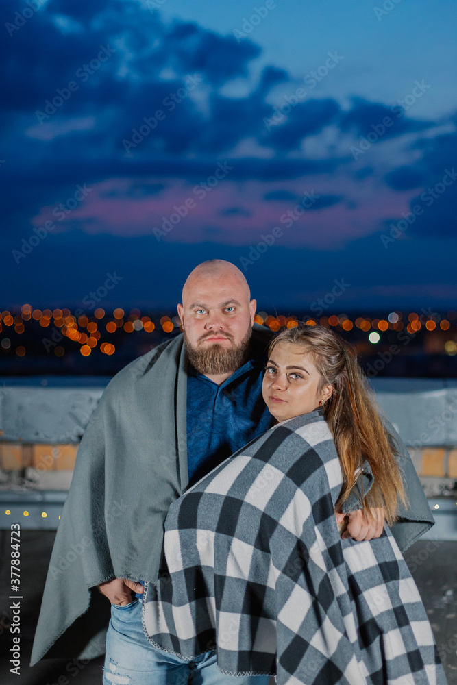 Beautiful couple on the roof under a blanket in the evening. Beautiful couple on the roof under a blanket in the evening.