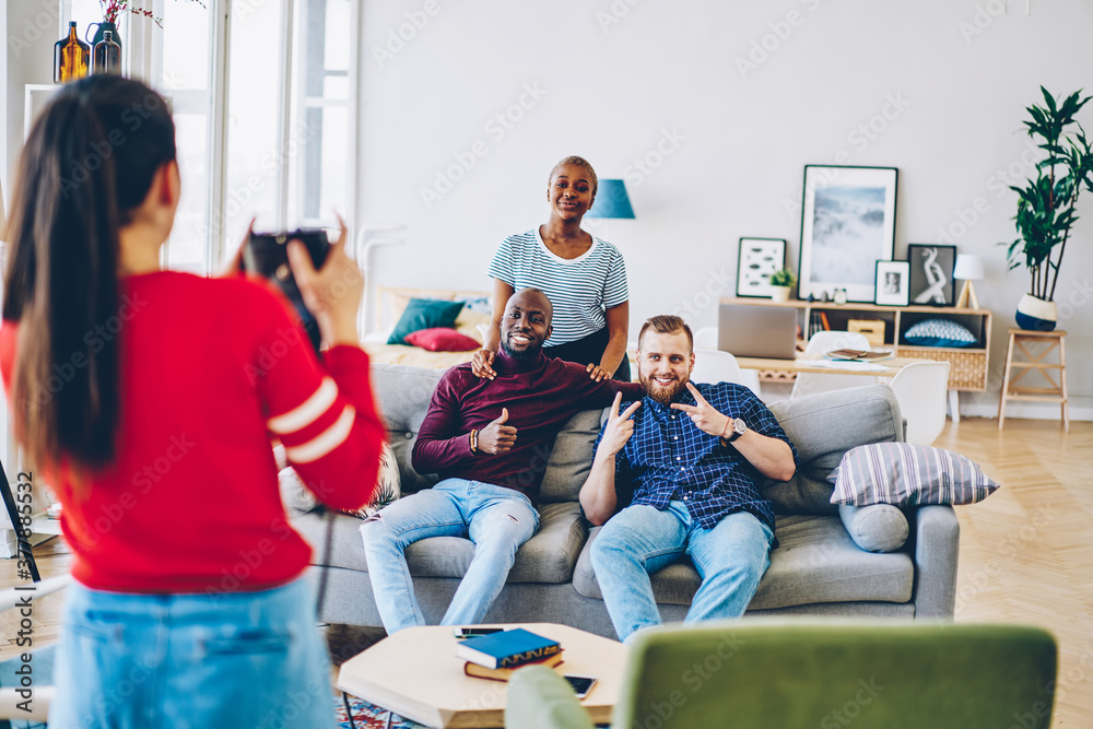 Naklejka premium Cheerful diverse friends posing for picture in living room