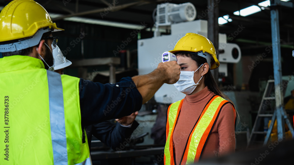 Industrial worker and engineer stand in line to check flu with infrared thermometer before enter to work and protect Coronavirus or Covid-19, safety and protection as working in manufacturing Industrial worker and engineer stand in line to check flu with infrared thermometer before enter to work and protect Coronavirus or Covid-19, safety and protection as working in manufacturing