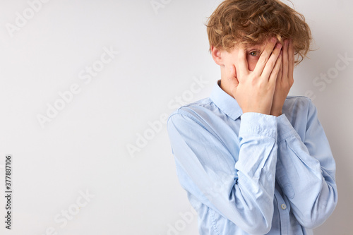 Canvas-taulu frightened boy closed his face with hands, 14-15 years old caucasian teenager is