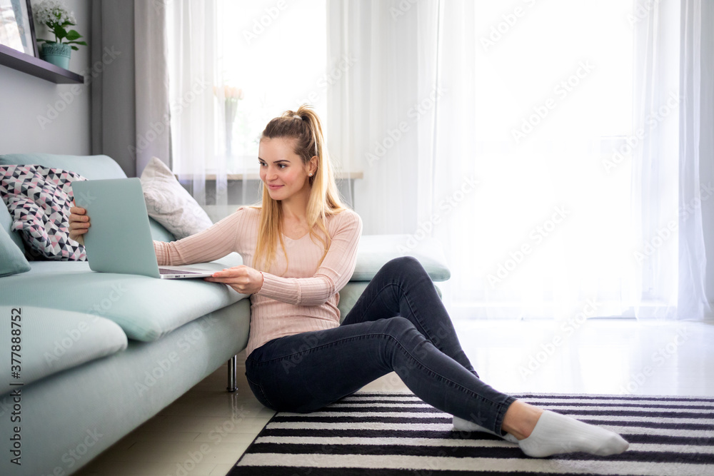 Relaxed woman enjoying time at home using laptop sitting near sofa Relaxed woman enjoying time at home using laptop sitting near sofa