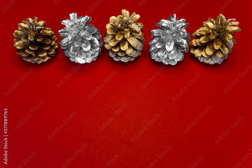 Fototapeta premium Christmas red background with silver and gold cones. Copy space, top view.
