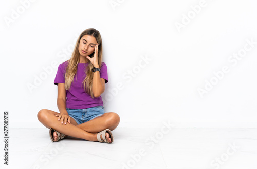 Young hispanic woman sitting on the floor with headache