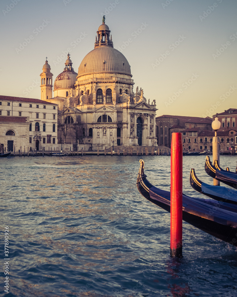 Basilica Santa Maria della Salute with docked gondolas in the foreground during a sunrise in Venice, Italy