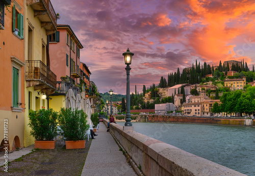 Fototapeta Naklejka Na Ścianę i Meble -  Embankment of Adige river in Verona, Italy. Sunset cityscape of Verona