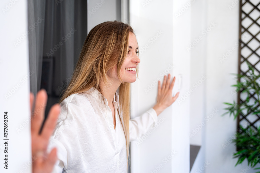 Cheerful beautiful woman standing in window at home Cheerful beautiful woman standing in window at home