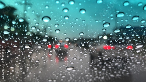 Rain falling on car windshield,colorful bokeh with street light,drive car on the road in city at heavy rain storm,blurred view,selective focus. photo