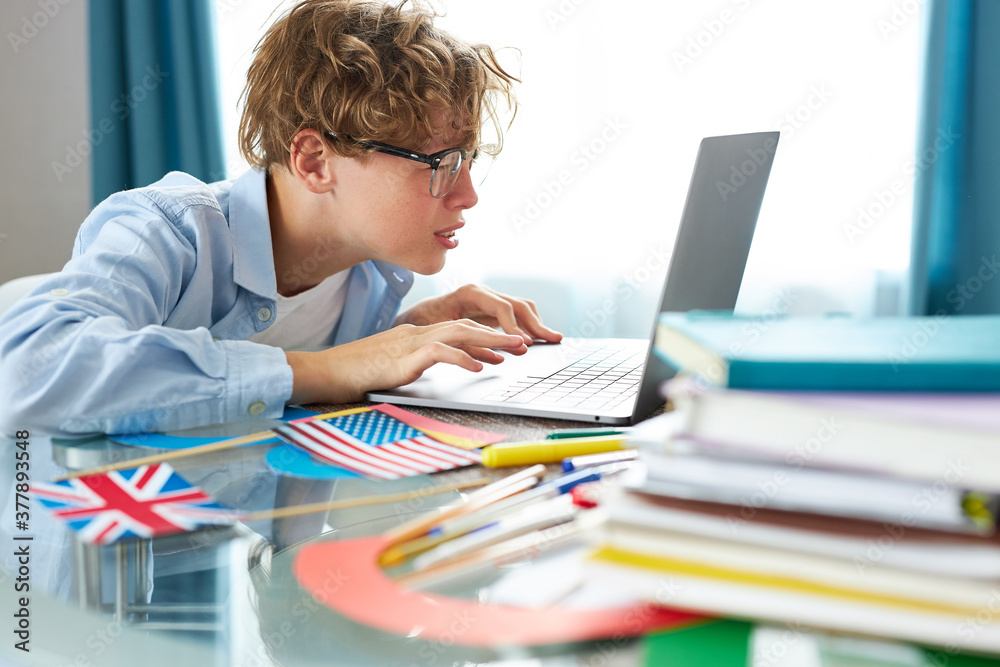 caucasian schoolboy studying at home looking at tutor at laptop screen during quarantine isolation period, teacher giving lesson online on video chat caucasian schoolboy studying at home looking at tutor at laptop screen during quarantine isolation period, teacher giving lesson online on video chat