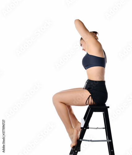 Slim fit girl on chair bends to left studio shot