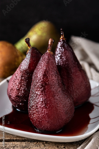 Poached pears in red wine on wooden table. 