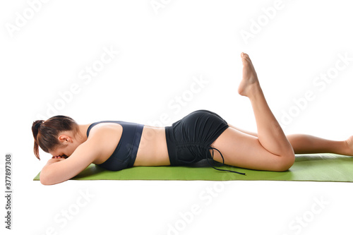 Athletic girl lies on a sports mat face down and meditates after yoga exercises.