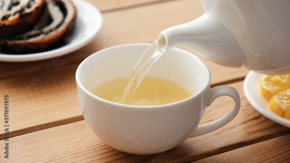 Pouring green tea in white porcelain cup. Closeup view Pouring green tea in white porcelain cup. Closeup view
