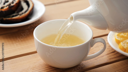 Pouring green tea in white porcelain cup. Closeup view